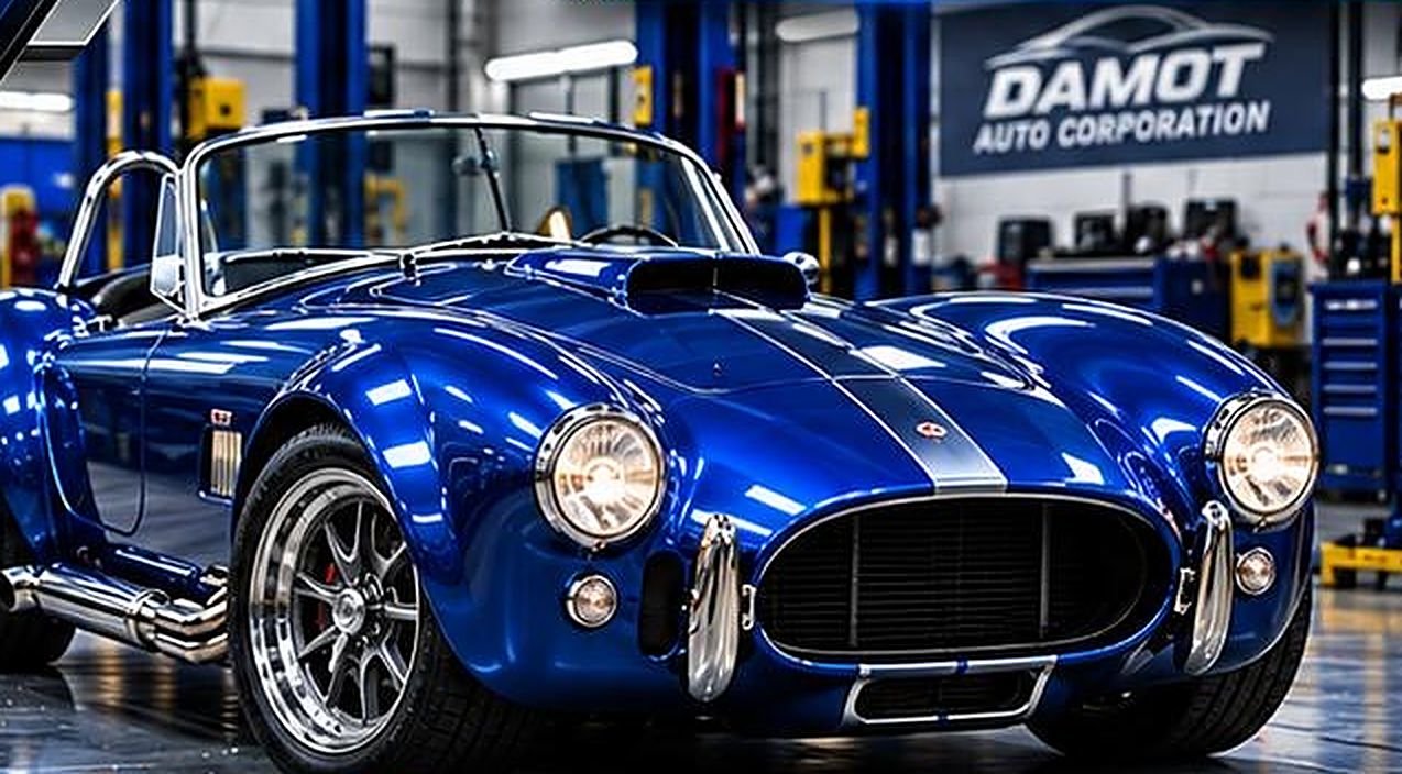 Restored blue roadster with silver racing stripes on the Damot shop floor
